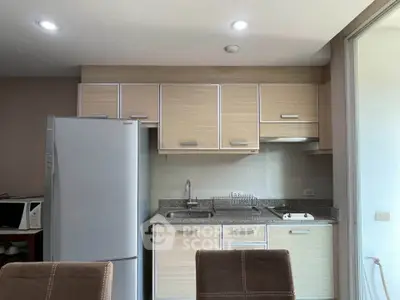 Modern kitchen with sleek cabinets and stainless steel fridge in a cozy apartment.