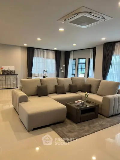 Spacious modern living room with elegant beige sofa and large windows.