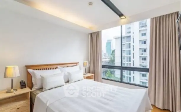 Modern bedroom with large window and city view in a high-rise apartment.