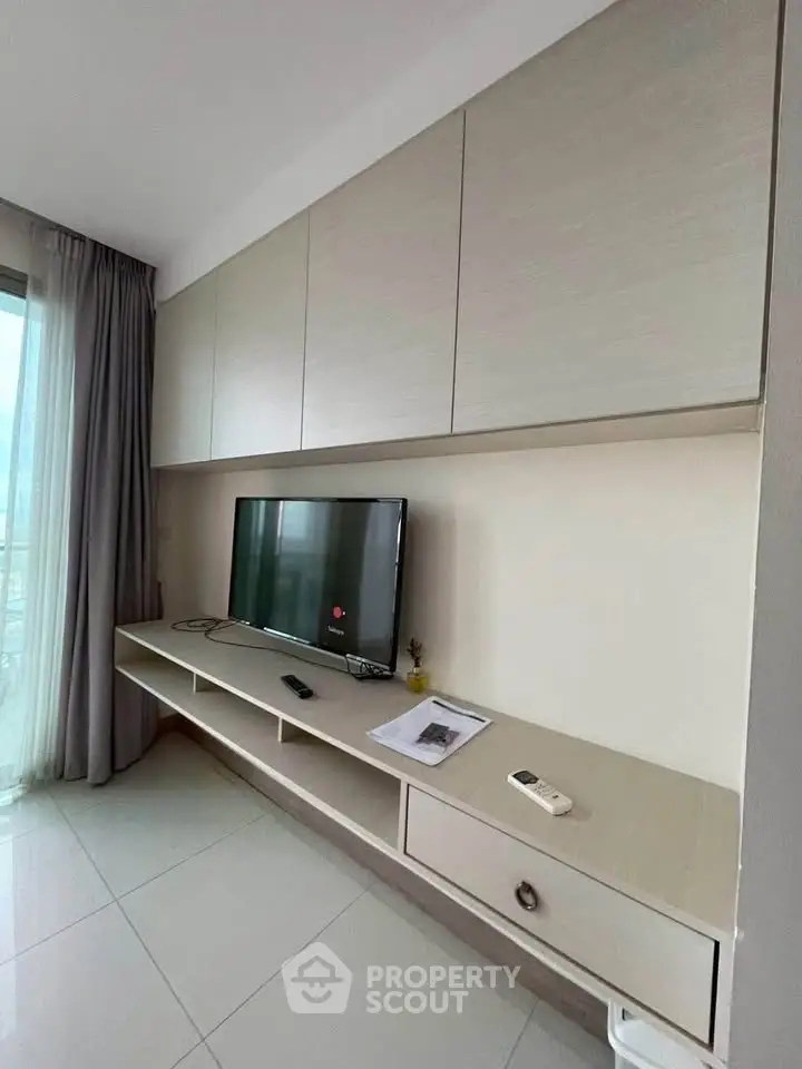 Modern living room with sleek TV unit and large window for natural light.