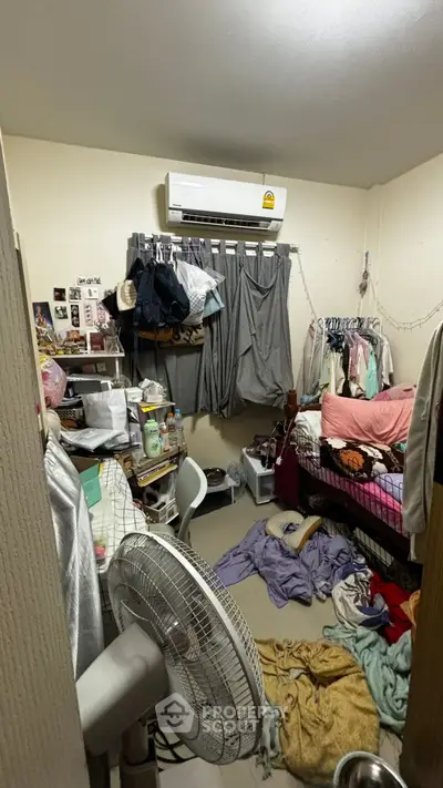 Cozy bedroom with air conditioning, cluttered with personal items and clothes, ideal for creative organization.