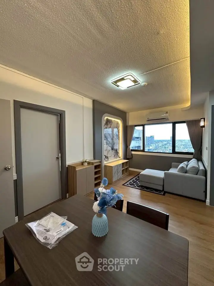 Modern living room with city view, stylish decor, and cozy seating area in a high-rise apartment.