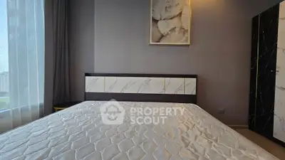 Modern bedroom with stylish decor and large window offering natural light.