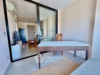 Modern apartment interior with glass partition, sleek furniture, and natural light.