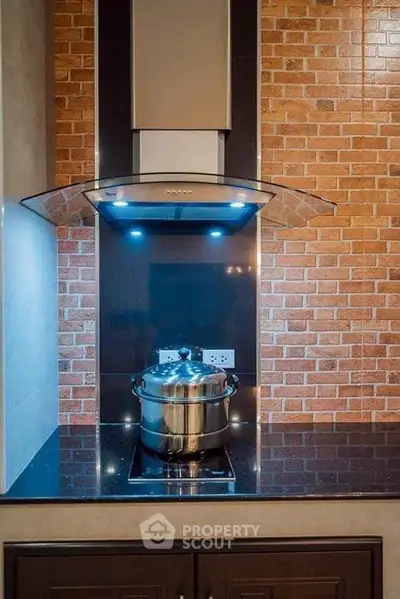 Modern kitchen with sleek stovetop and stylish brick backsplash