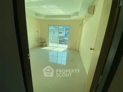 Bright empty room with large window and air conditioning, ideal for customization.