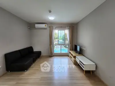 Spacious living room with modern sofa and TV, overlooking a pool view through large windows.