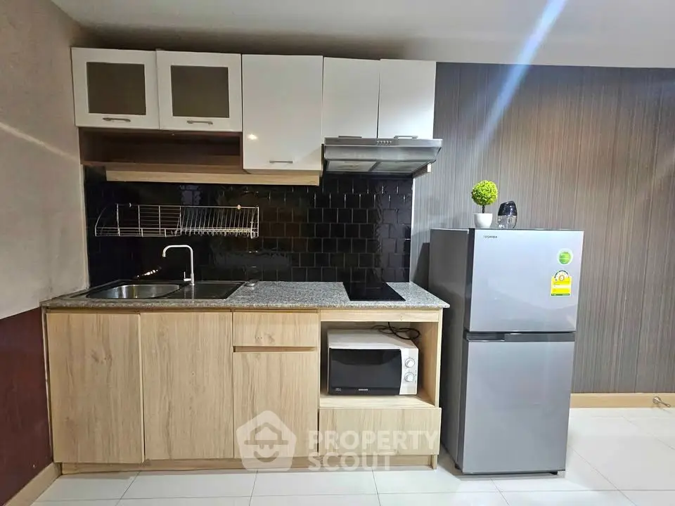 Modern compact kitchen with sleek cabinets, granite countertop, and stainless steel appliances in a stylish apartment.