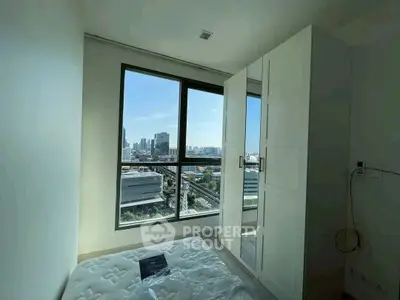 Bright bedroom with large window offering stunning city view and modern wardrobe.
