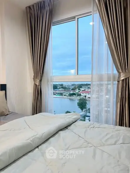 Cozy bedroom with elegant curtains and stunning river view from the window.