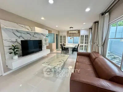 Luxurious living room with marble accents and spacious layout, featuring modern furniture and large windows.