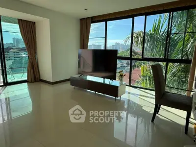 Spacious living room with large windows offering stunning city views and abundant natural light.