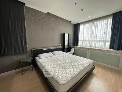 Spacious bedroom with modern decor and large window offering natural light