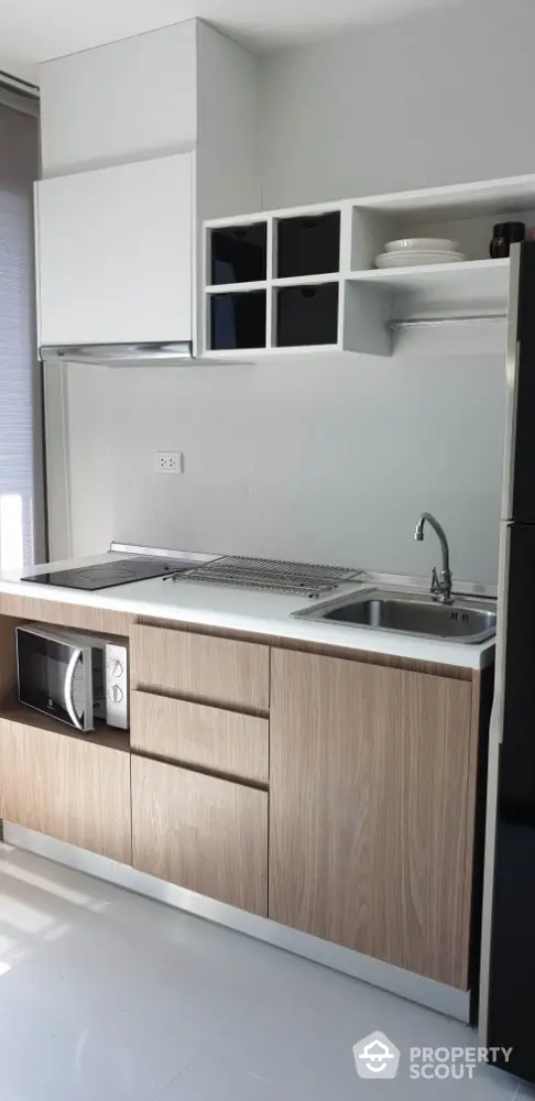 Modern kitchen with sleek cabinetry and built-in microwave in a compact layout.