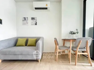 Modern living room with stylish gray sofa and dining area, featuring minimalistic decor and air conditioning.