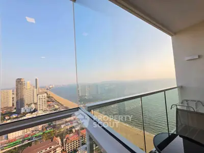 Stunning ocean view from a high-rise balcony with glass railing, perfect for relaxation.