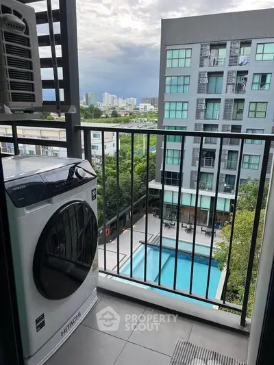 Modern apartment balcony with washing machine and stunning pool view in urban setting.
