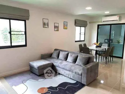 Modern living room with stylish gray sofa and dining area in open layout apartment.