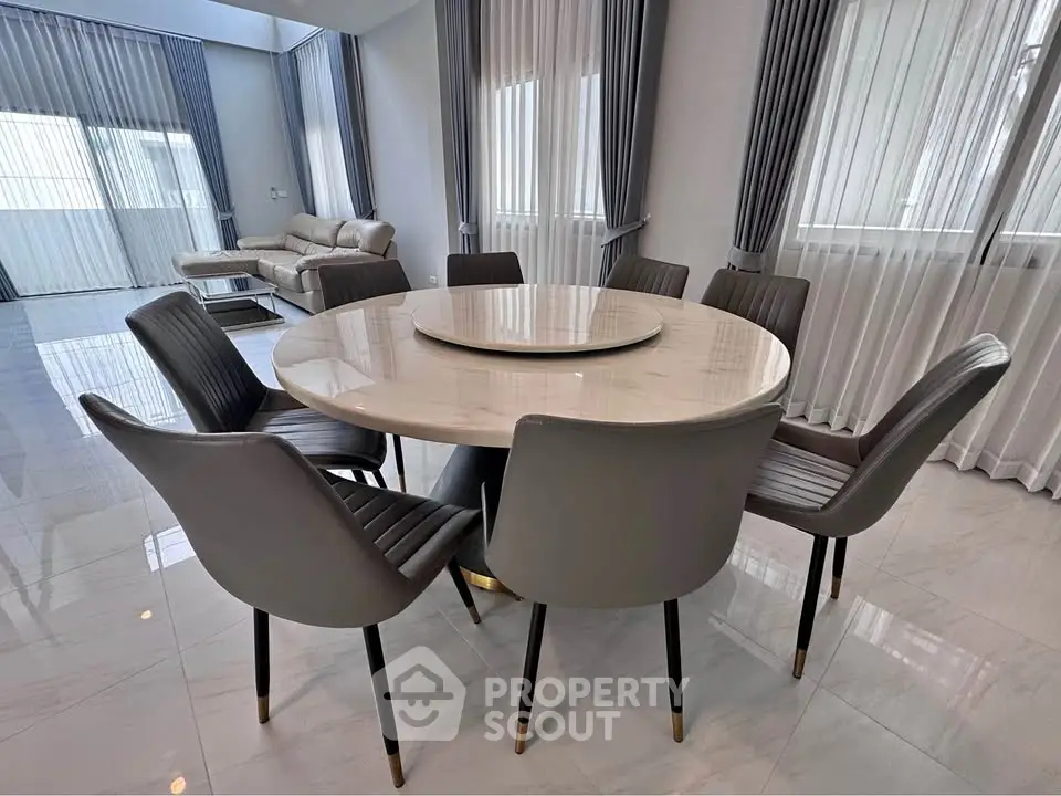 Elegant dining area with round marble table and modern chairs in a spacious living room.