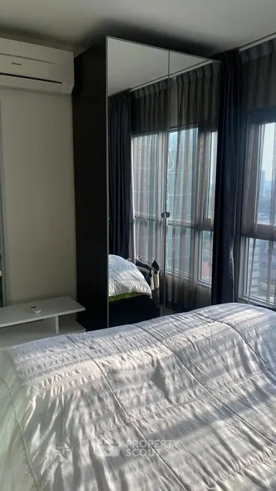 Modern bedroom with large windows and mirrored wardrobe in a high-rise apartment.