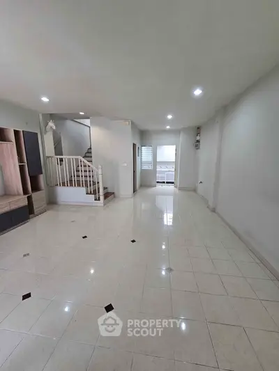 Spacious open-plan living area with tiled flooring and modern staircase, perfect for family gatherings.
