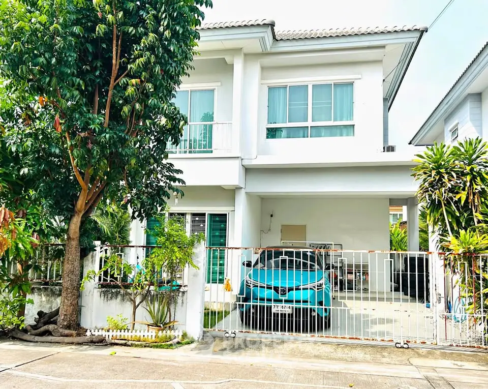 Charming two-story house with lush garden and carport in serene neighborhood.