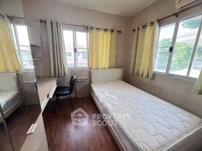Cozy bedroom with natural light, featuring a comfortable bed and study area, perfect for relaxation and productivity.