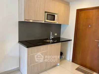 Modern compact kitchen with sleek cabinetry and built-in microwave in a stylish apartment.