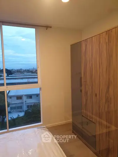 Modern bedroom with large window and wooden wardrobe offering serene views.