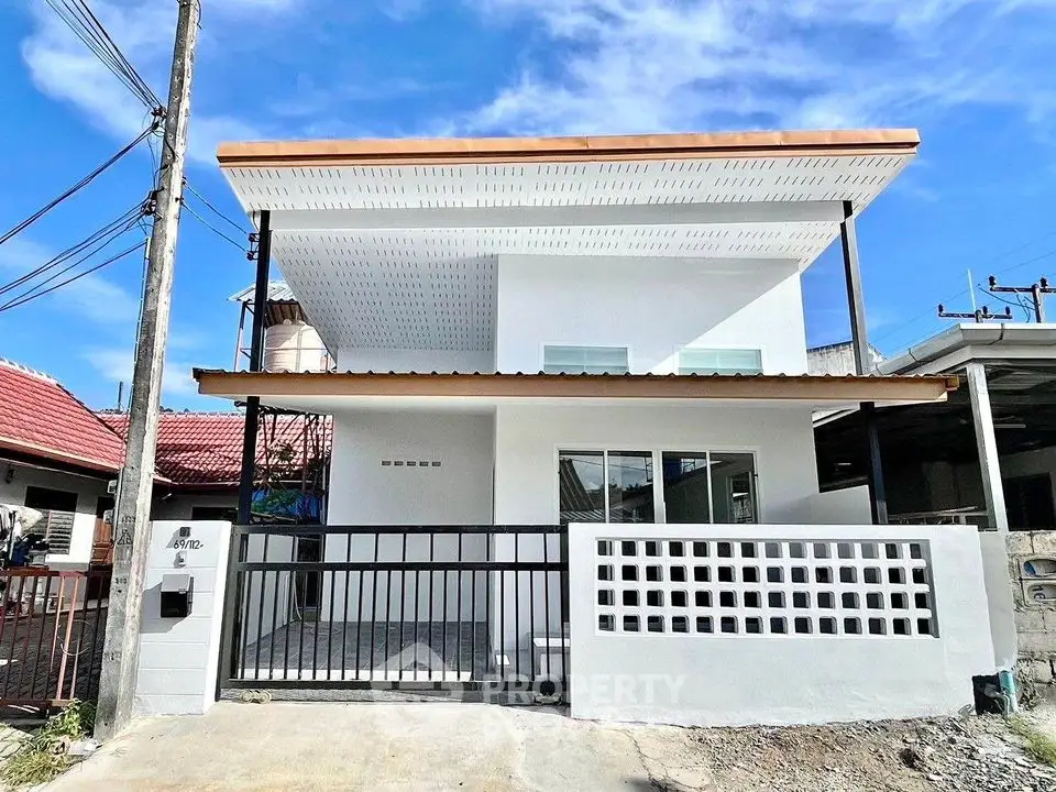 Modern two-story house with sleek design and spacious balcony under clear blue sky.
