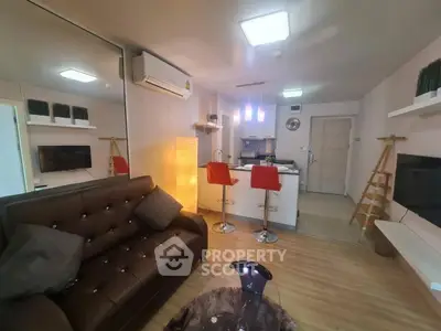 Modern living room with stylish decor and open kitchen layout, featuring a cozy sofa and bar stools.