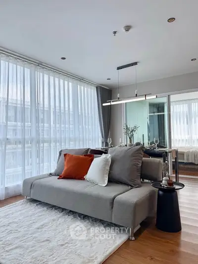 Modern living room with stylish sofa, floor-to-ceiling windows, and elegant decor in a bright apartment.