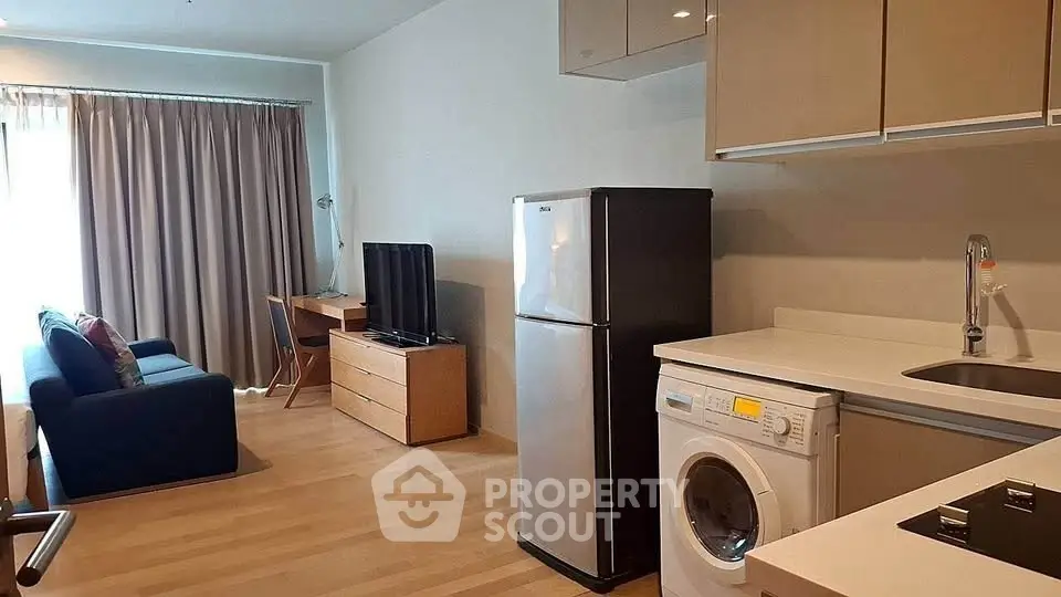 Modern studio apartment with open kitchen, washing machine, and cozy living area.