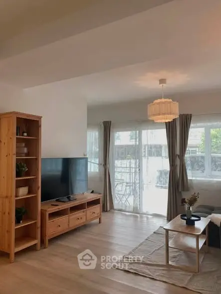 Spacious living room with natural light, wooden furniture, and modern decor.