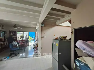 Spacious open-layout living area with exposed beams and natural light, featuring a cozy workspace and modern appliances.