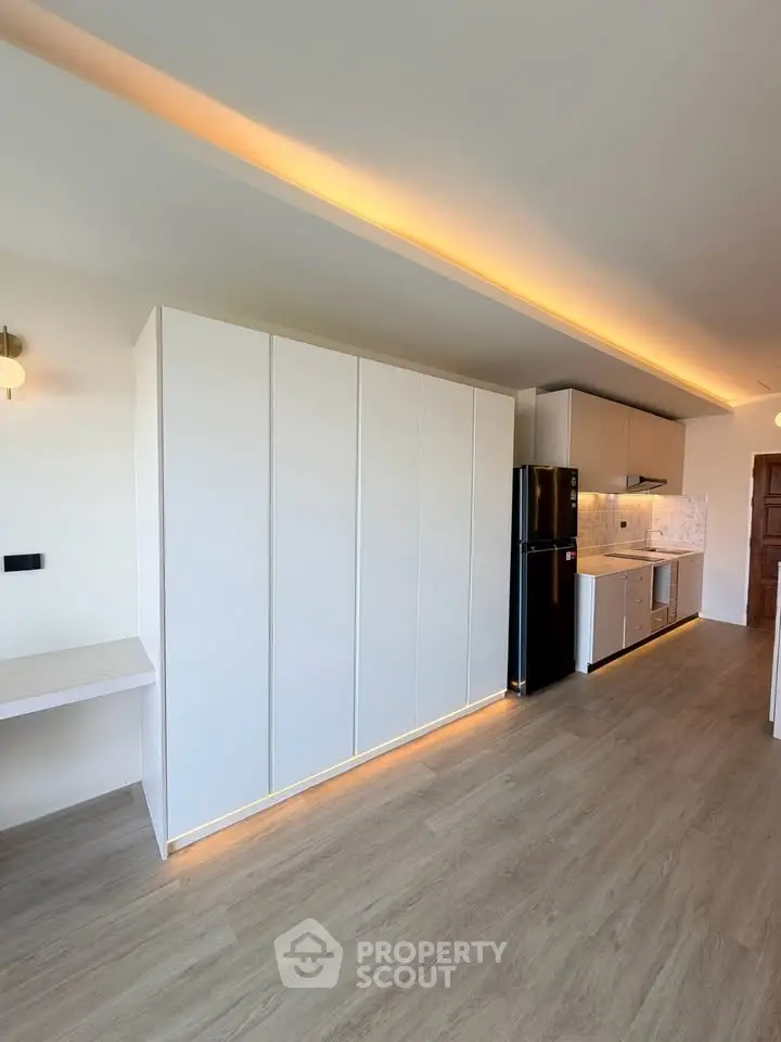 Modern kitchen with sleek cabinetry and integrated appliances in open layout apartment.