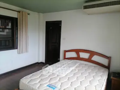 Spacious bedroom with wooden bed frame and air conditioning unit.