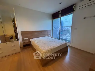 Spacious bedroom with wooden flooring and large window in modern apartment