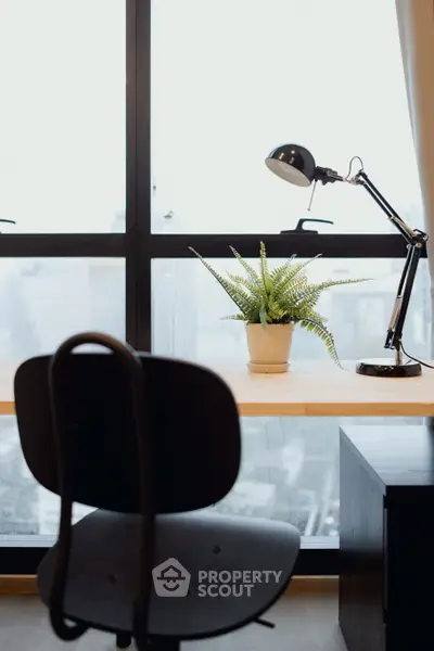 Modern study area with desk lamp and potted plant by large window