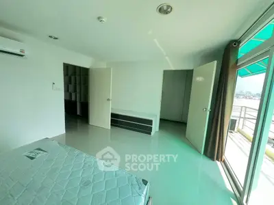 Spacious bedroom with balcony access and ample natural light in modern apartment.