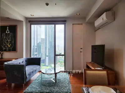 Modern living room with city view, stylish furniture, and large windows in a high-rise apartment.