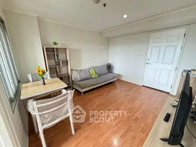 Cozy living room with wooden flooring, modern sofa, and dining area in a bright apartment.