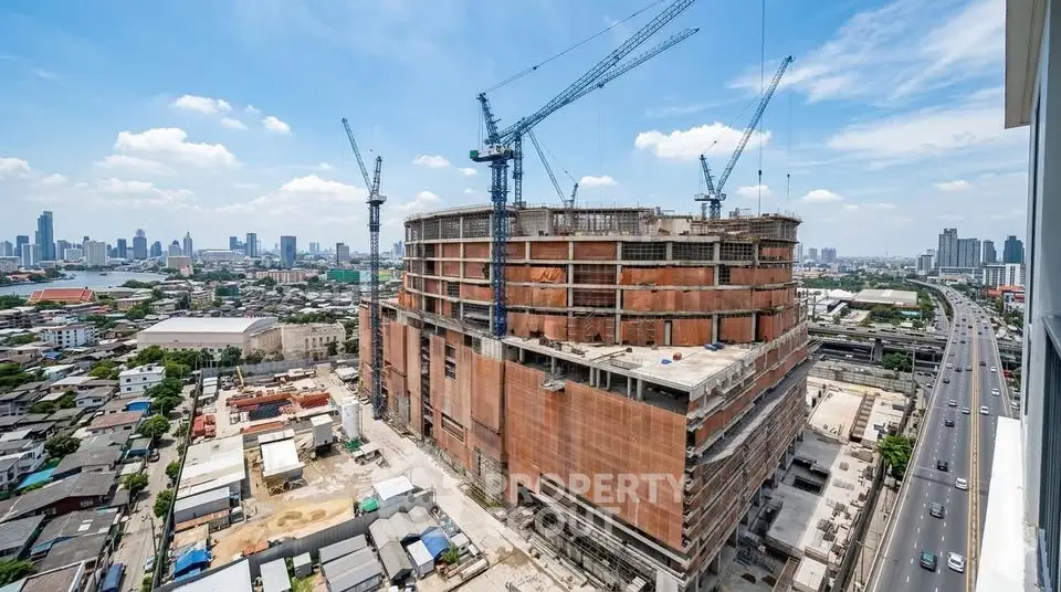 High-rise building under construction with cranes and city skyline view