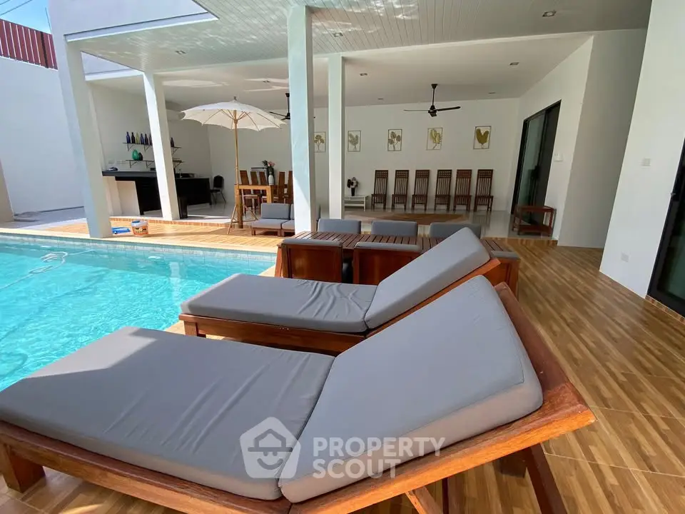 Luxurious poolside patio with stylish wooden loungers and modern outdoor dining area.