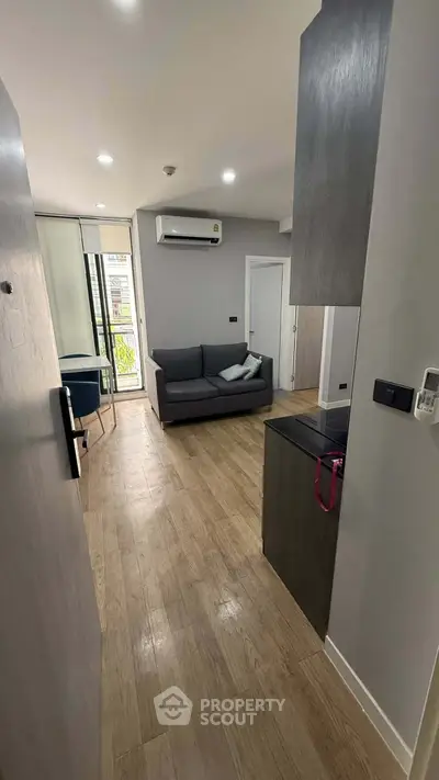 Modern living room with sleek design and wooden flooring, featuring a cozy sofa and air conditioning.