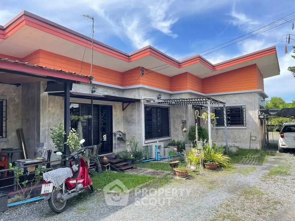Charming single-story home with vibrant orange accents and lush garden.