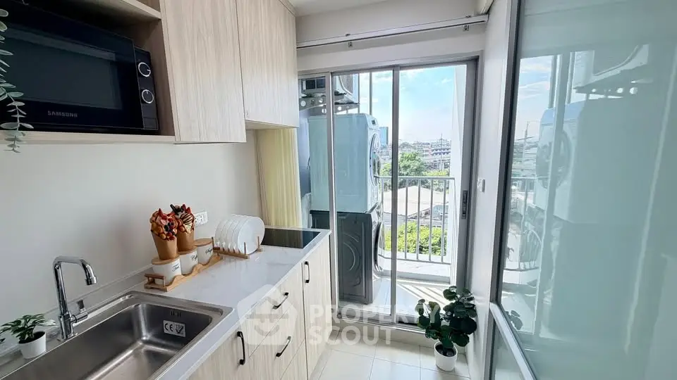 Modern kitchen with sleek cabinetry and balcony view, featuring a microwave and washing machine.