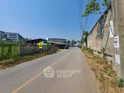 Scenic road view with nearby residential and commercial buildings under clear blue sky.