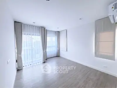Spacious empty room with large windows and elegant curtains, perfect for customization.