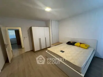 Spacious bedroom with modern design and ample natural light, featuring a large wardrobe and comfortable bed.